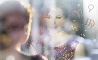 woman looking at reflection in mirror with zodiac sign symbols